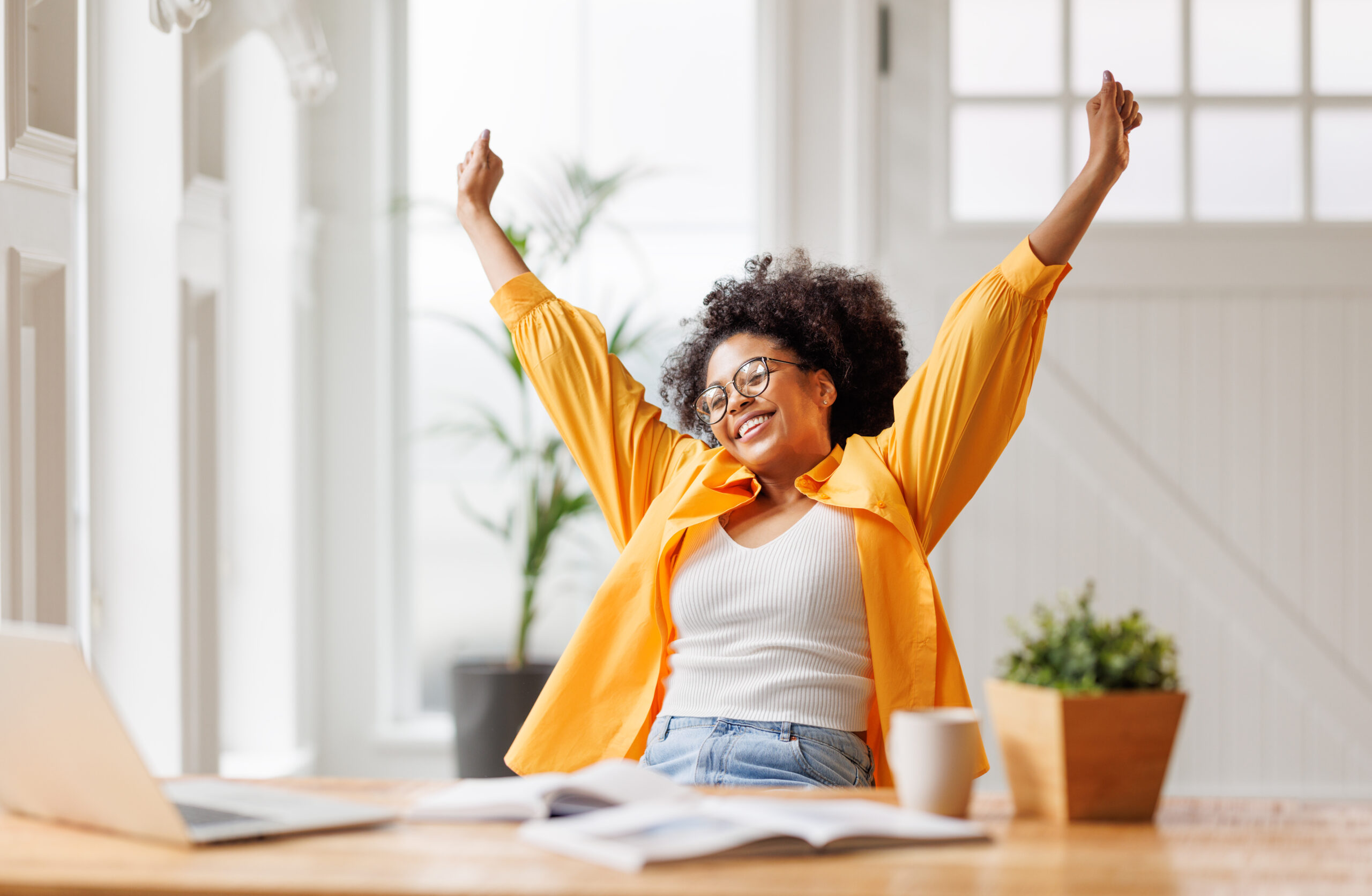 woman with her arms in the air happy in front of a laptop. Start your own business